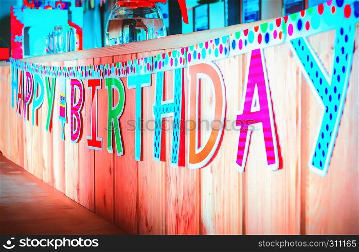 Motley Happy Birthday banner hanging on a wooden background. Selective focus.. Happy Birthday Paper Inscription