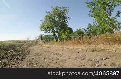 Motocross biker riding enduro motorcycle on dirt track kicking up dust