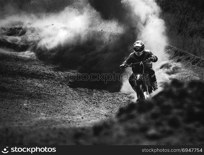 Motocross racer accelerating in dust track, Black and white photo. Motocross racer accelerating in dust track, Black and white, high contrast photo