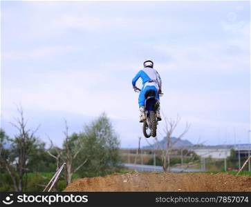 Motocross racer giving a jump with his bike.&#xA;