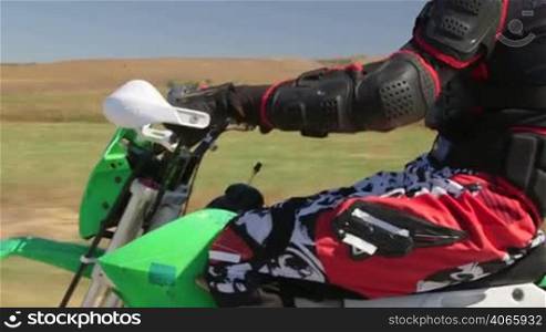 Motocross racer riding dirt bike, vehicle shot side view closeup tilt up/down