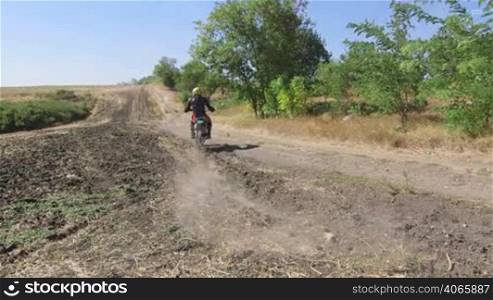 Motocross rider on his enduro bike riding away kicking up dust