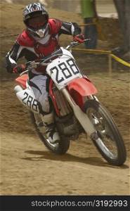 Motocross rider riding a motorcycle and leaning into a turn