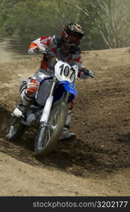 Motocross rider riding a motorcycle on a dirt road