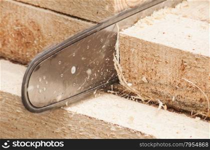 Motor chainsaw cutting wooden beam closeup