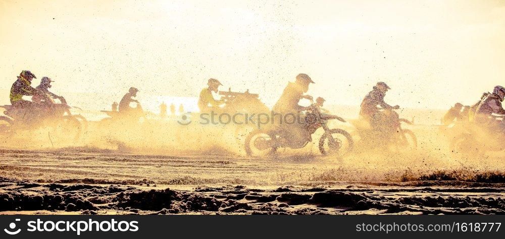 Motor crossers are racing on the beacht against the setting sun