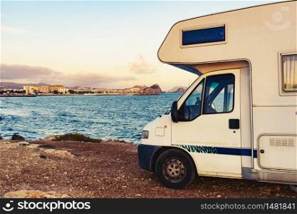 Motor home on spanish coast sea shore. Aguilas city in the distance. Murcia region, Spain. Visiting warm winter travel destinations.. Motor home on sea shore, Spain