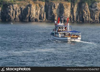 Motor yacht with passengers against the background of steep cliffs. Sozopol. Bulgaria