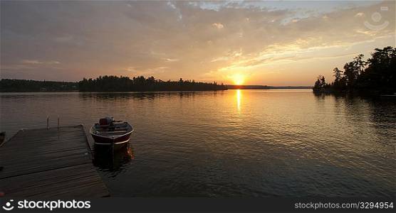 Motorboat at the dock with the sunsest in the horizon in Lake of the Woods, Ontario