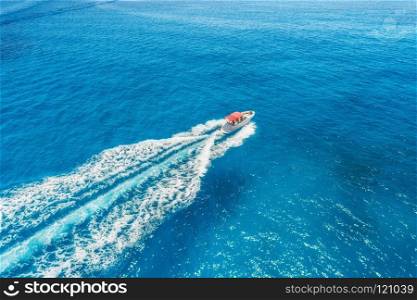 Motorboat at the sea in balearic islands. Aerial view of floating boat with people in transparent blue water at sunny day. Summer landscape. Top view from drone. Seascape with yacht in motion in bay