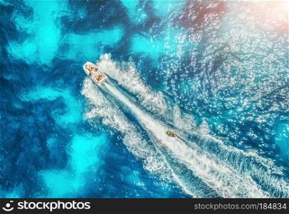 Motorboat at the sea in balearic islands at sunset in summer. Aerial view of floating boat with people in transparent blue water. Landscape. Top view from drone. Seascape with yacht in motion in bay