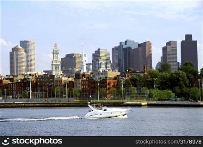 Motorboat in a harbor in front of a Boston skyline on a sunny summer day