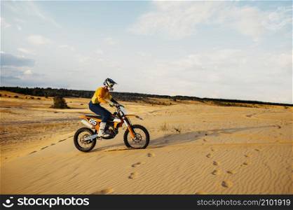 Motorcross riding over sand in desert dune. Professional bike pilot, extreme speed racing. Motorcross riding over sand in desert dune