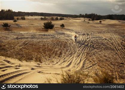 Motorcycle riding in sand dune terrain view from afar. Motorcyclist practicing motocross racing. Motorcycle riding in sand dune top view