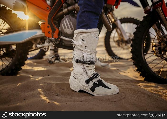 Motorcycle trials during motocross competition. Closeup rider boots. Motorcyclist team ready to start. Motorcycle trials during motocross competition closeup rider boots
