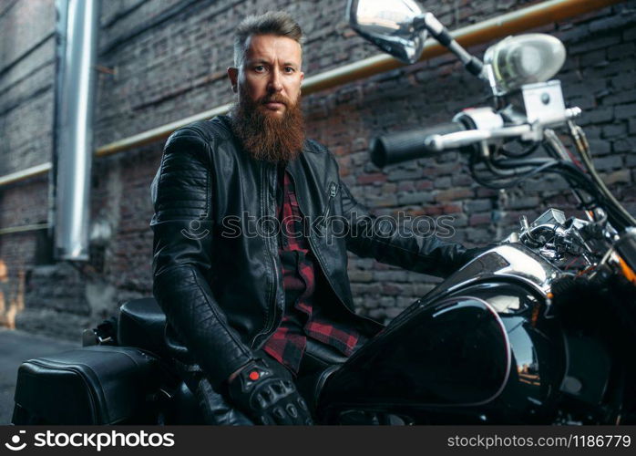 Motorcyclist poses on classical chopper, biker. Vintage bike rider on motorcycle, freedom lifestyle