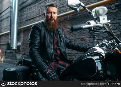 Motorcyclist poses on classical chopper, biker. Vintage bike rider on motorcycle, freedom lifestyle