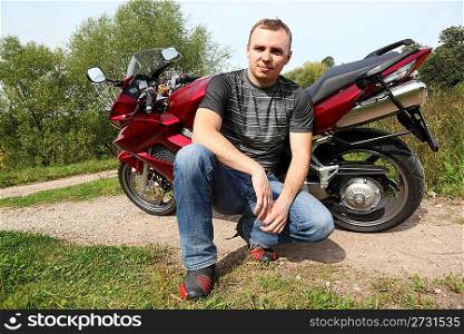 motorcyclist sitting on country road near bike
