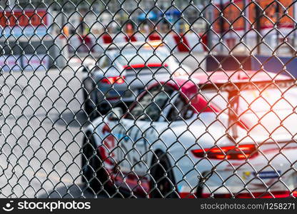 Motorsport car racing on asphalt road. View from the fence mesh netting on blurred car on racetrack background. Super racing car on street circuit. Automotive industry concept.