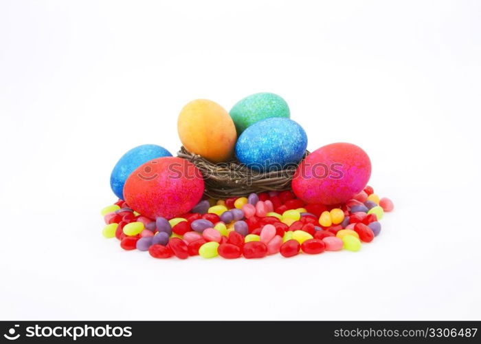 Mottle colored Easter eggs in a natural twig nest sit on colorful jelly beans