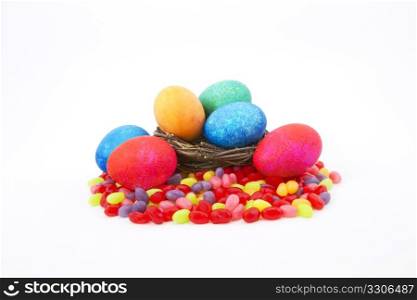 Mottle colored Easter eggs in a natural twig nest sit on colorful jelly beans