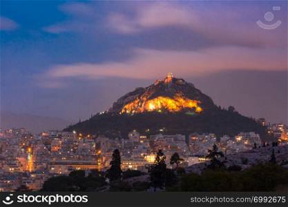 Mount Lycabettus towering above of the roofs of Old Town at sunset in Athens, Greece. Mount Lycabettus in Athens, Greece