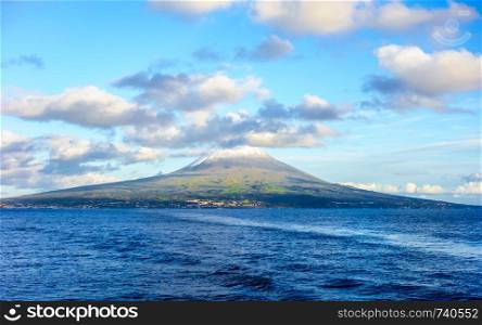 Mount Pico volcano western slope viewed from ocean with summit in clouds, in Azores, Portugal.