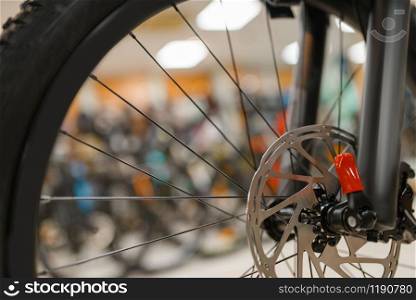 Mountain bicycle in sports shop, focus on front wheel, nobody. Summer active leisure, showcase with bikes, cycle sale, professional biking equipment. Bicycle in sports shop, focus on front wheel