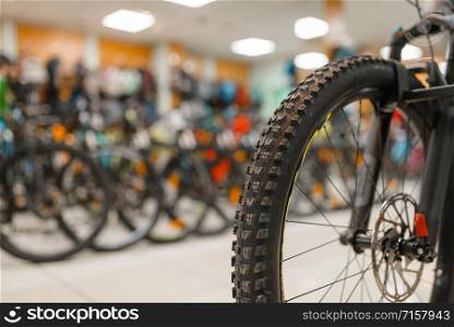 Mountain bicycle in sports shop, focus on front wheel, nobody. Summer active leisure, showcase with bikes, cycle sale, professional biking equipment