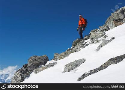Mountain climber descending snow and boulder slope