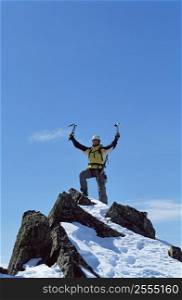 Mountain climber standing on snowy mountain victorious and smiling