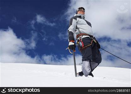 Mountain climber standing on snowy slope with safety line attached