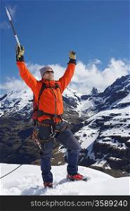 Mountain climber with arms raised on top of snowy peak