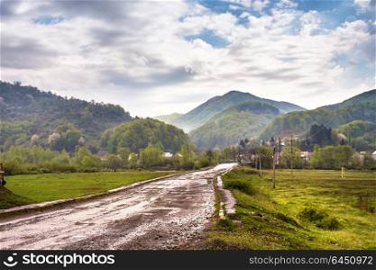 Mountain countryside. Road and village in green mountain valley. Spring stormy rainy weather