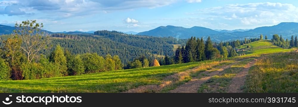 Mountain evening panorama view with earth road, haystackes and country estate (Carpathian Mts, Ukraine).