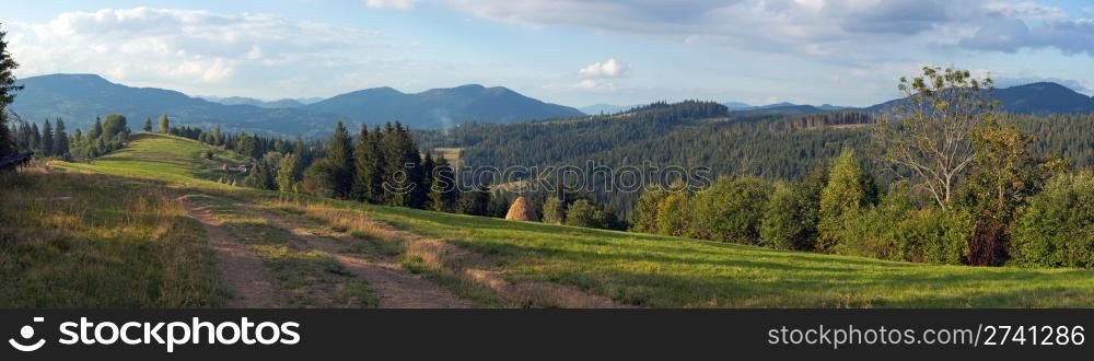 Mountain evening panorama view with earth road, haystackes and country estate (Slavske village outskirts, Carpathian Mts, Ukraine). Nine shots composite picture.