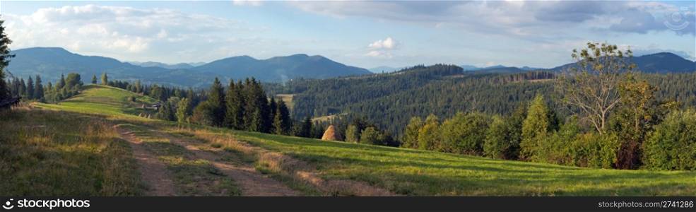 Mountain evening panorama view with earth road, haystackes and country estate (Slavske village outskirts, Carpathian Mts, Ukraine). Nine shots composite picture.