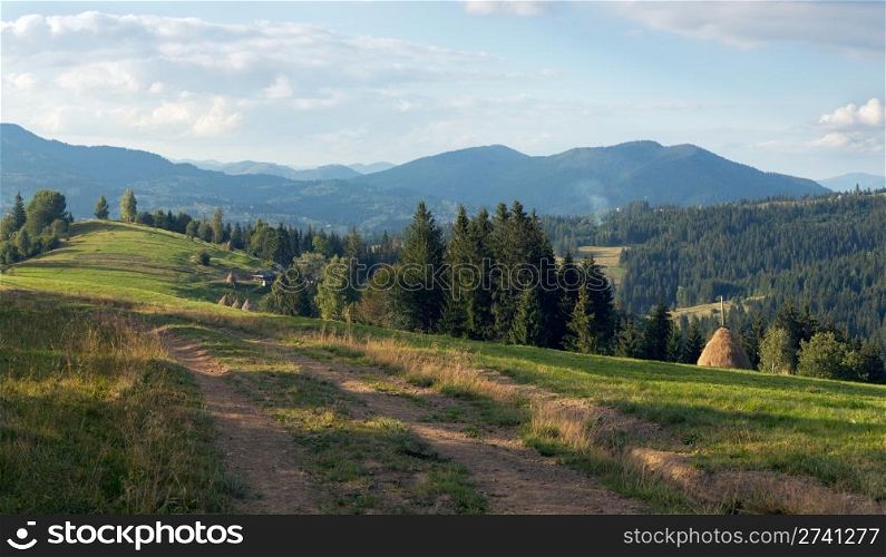 Mountain evening view with earth road, haystackes and country estate (Slavske village outskirts, Carpathian Mts, Ukraine). Four shots composite picture.