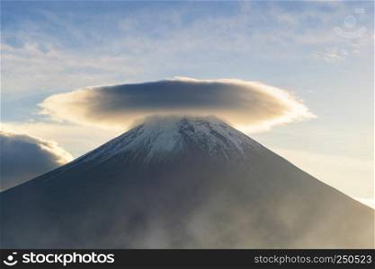 Mountain Fuji with hat-shaped cloud at blue sunrise sky with sunlight near Fujikawaguchiko, Yamanashi, Japan