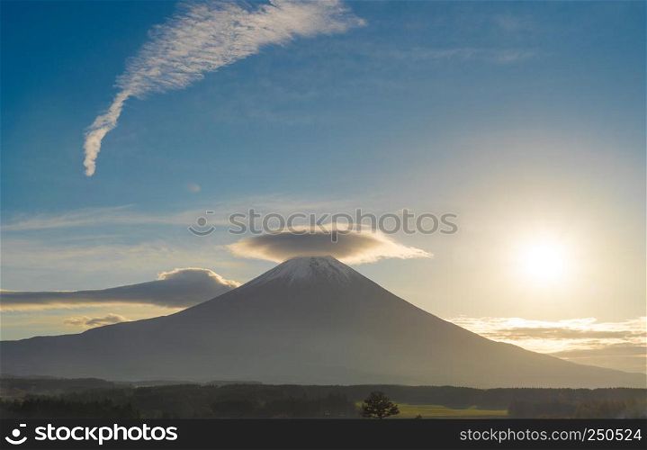 Mountain Fuji with hat-shaped cloud at blue sunrise sky with sunlight near Fujikawaguchiko, Yamanashi, Japan