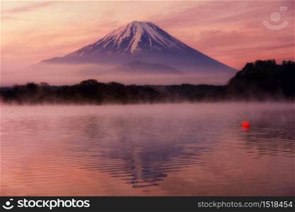 Mountain Fuji with skyline reflection and mist on water of lake Shoji Shojiko at dawn with twilight sky before sunrise, Yamanashi, Japan. Famous travel 5 lakes to see mount Fujisan.