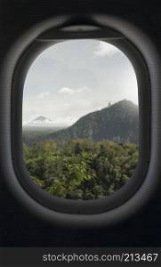 Mountain, green tropical forest and sky view from an airplane window. Go Travel booking concept. View from airplane window on tropical and mountains