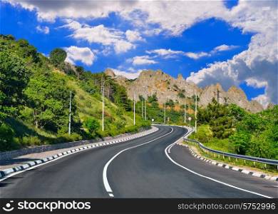 Mountain highway winds among mountain ranges against the blue sky