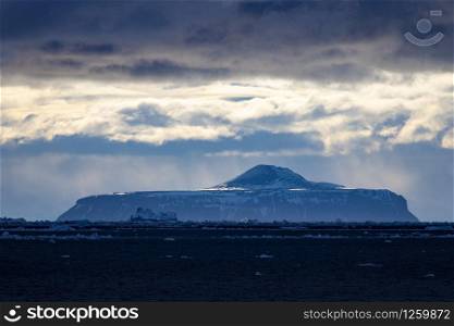 Mountain in Antarctica at dusk with beautiful rays of light against a blue horizon