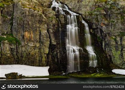 Mountain lake Flotvatnet with waterfall. Scenic region between Aurland and Laerdal in Norway. National tourist route Aurlandsfjellet.. Mountain lake waterfall Flotvatnet Norway