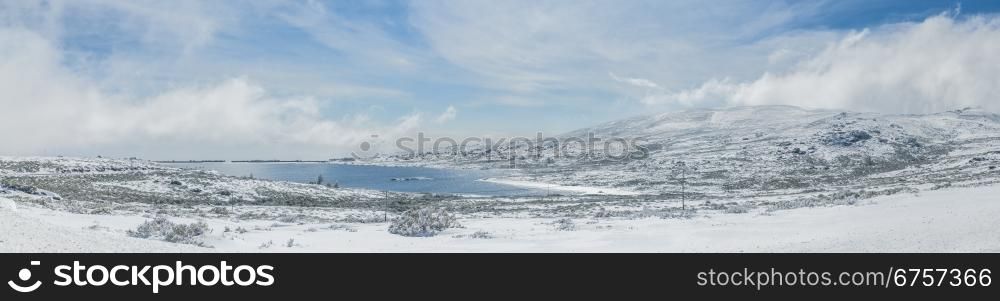 Mountain lake Viriato at Serra da Estrela, Portugal, covered by snow and clouds.