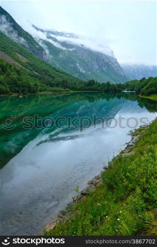 Mountain lake with clean water and mountains reflected (Norway, near Stordal). Summer cloudy view.