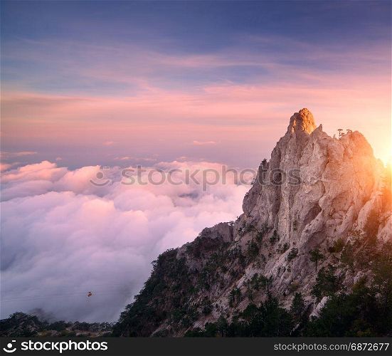 Mountain landscape at sunset. Amazing view from mountain peak on the high rocks, blue sky, pink clouds and in the evening. Low clouds. Colorful nature background. Adventure. Travel in Crimea. Cliffs. Mountain landscape at sunset. Amazing view from mountain peak