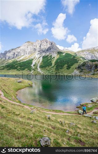 Mountain landscape: Rocky mountain range, clear water lake and blue cloudy sky