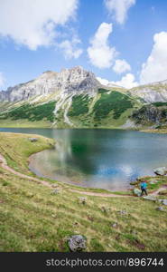 Mountain landscape: Rocky mountain range, clear water lake and blue cloudy sky